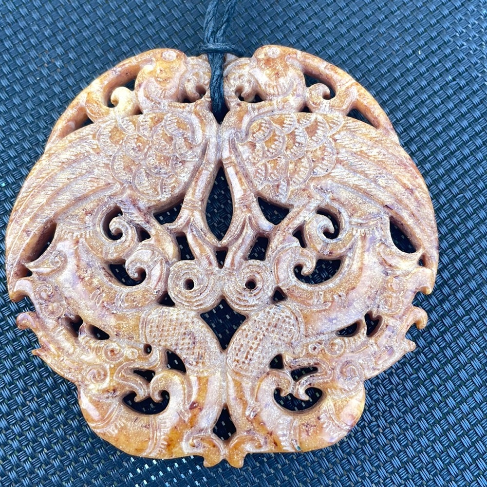 Carved stone pendant with black cord chain